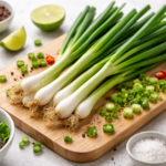 Fresh spring onions arranged on a wooden board with chopped green onions and herbs
